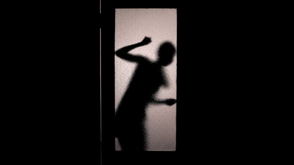 Woman silhouette behind door she is trapped behind due to false imprisonment