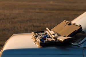 Long gun resting on the hood of a car against a bucolic background