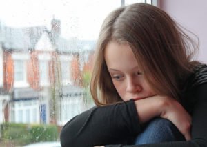 A child sex abuse victim sitting on a window seat close to tears following a CRS 18-3-405 violation