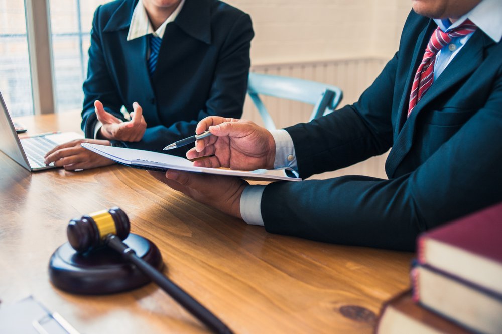 Attorney outlining a strategy to clear a bench warrant with his client, and they are sitting at a desk with law books and a gavel