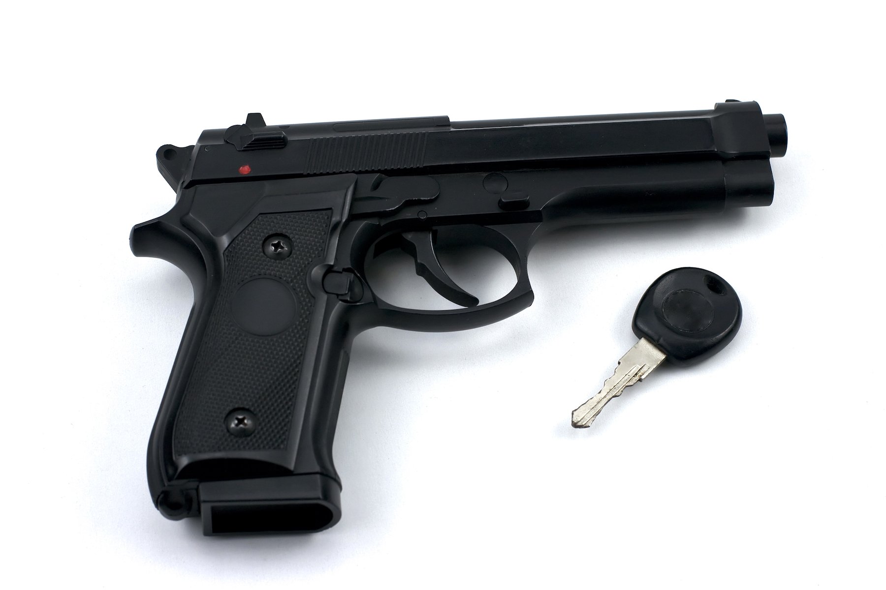 Handgun and car key against a white background