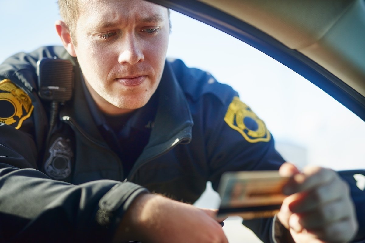 Police officer looking at a driver's license during a traffic stop during the day