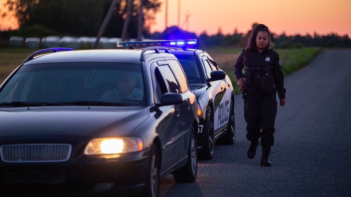 Policewoman at dusk conducting a traffic stop on a driver who is committing DARP