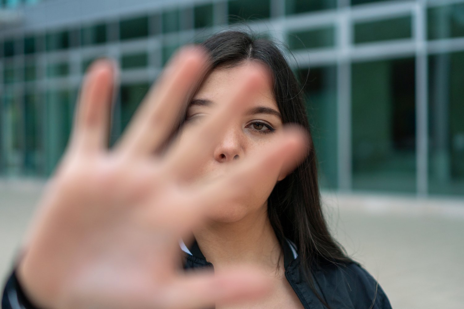 Harassment victim holding up her hand in defense while standing outside
