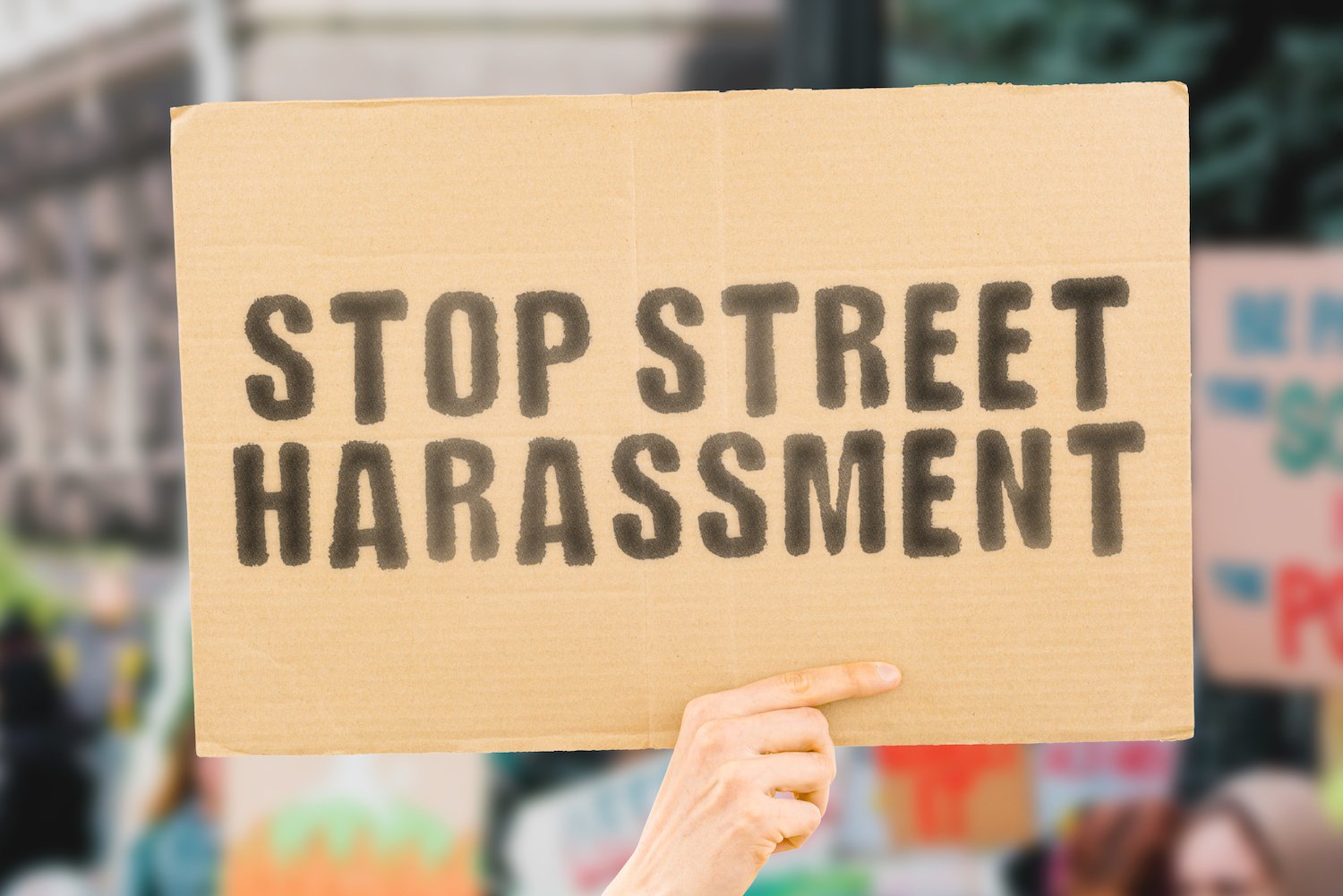 Cardboard sign that says "Stop Street Harassment" being held up by a hand