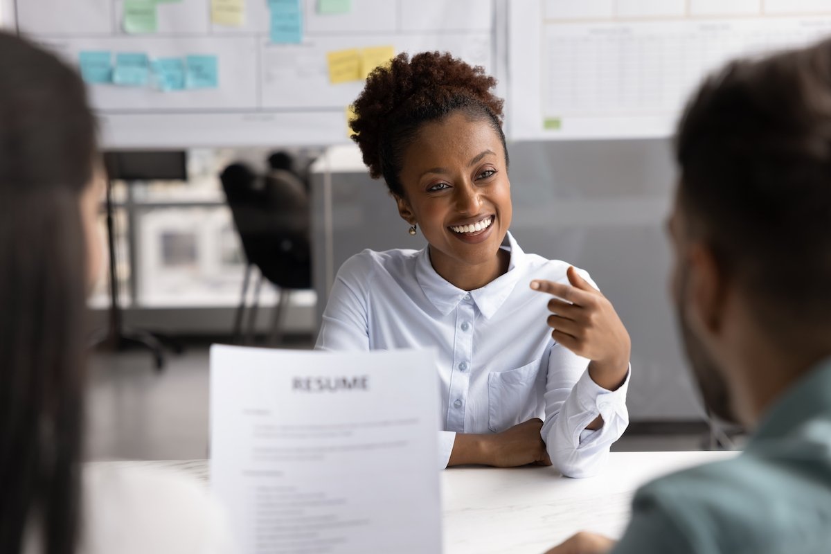 Happy lady interviewing for a job behind a desk of a recruiter holding her resume