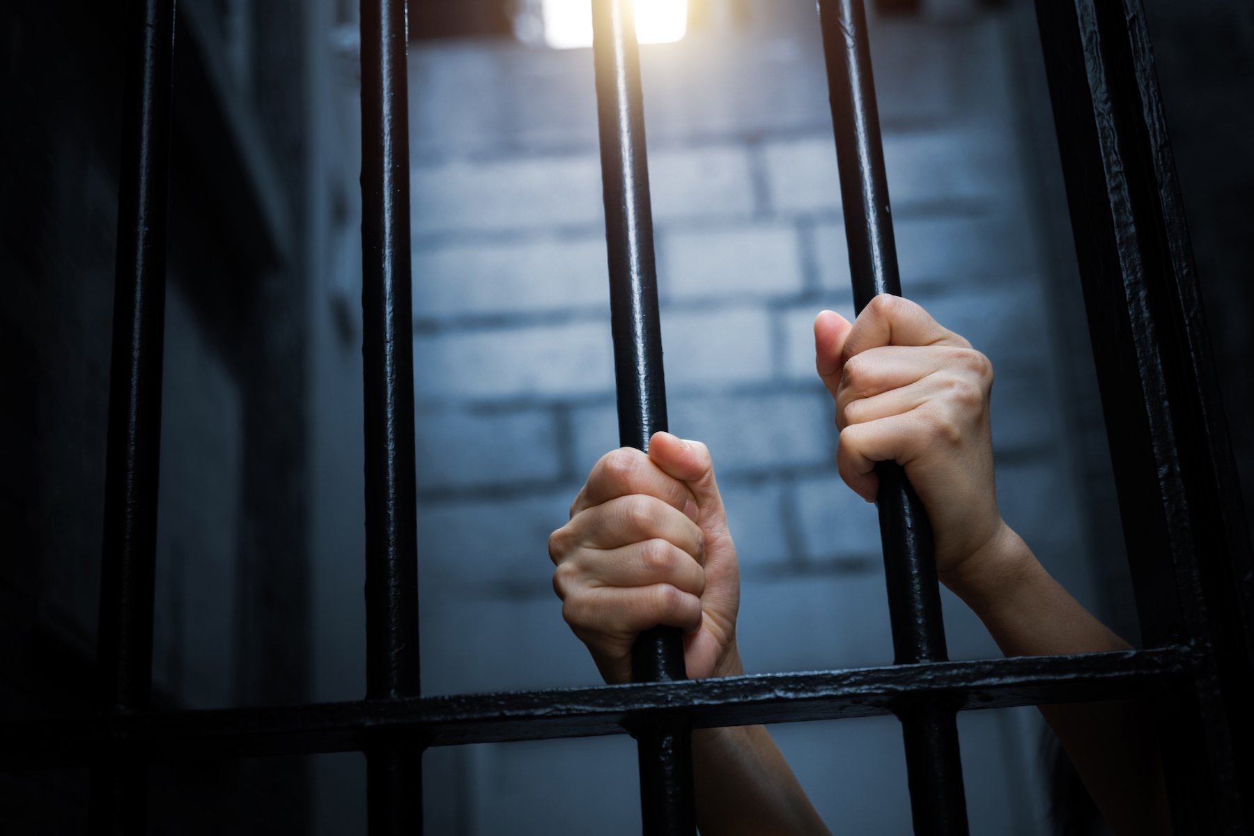 Rejas de celda de cárcel siendo agarradas por un recluso