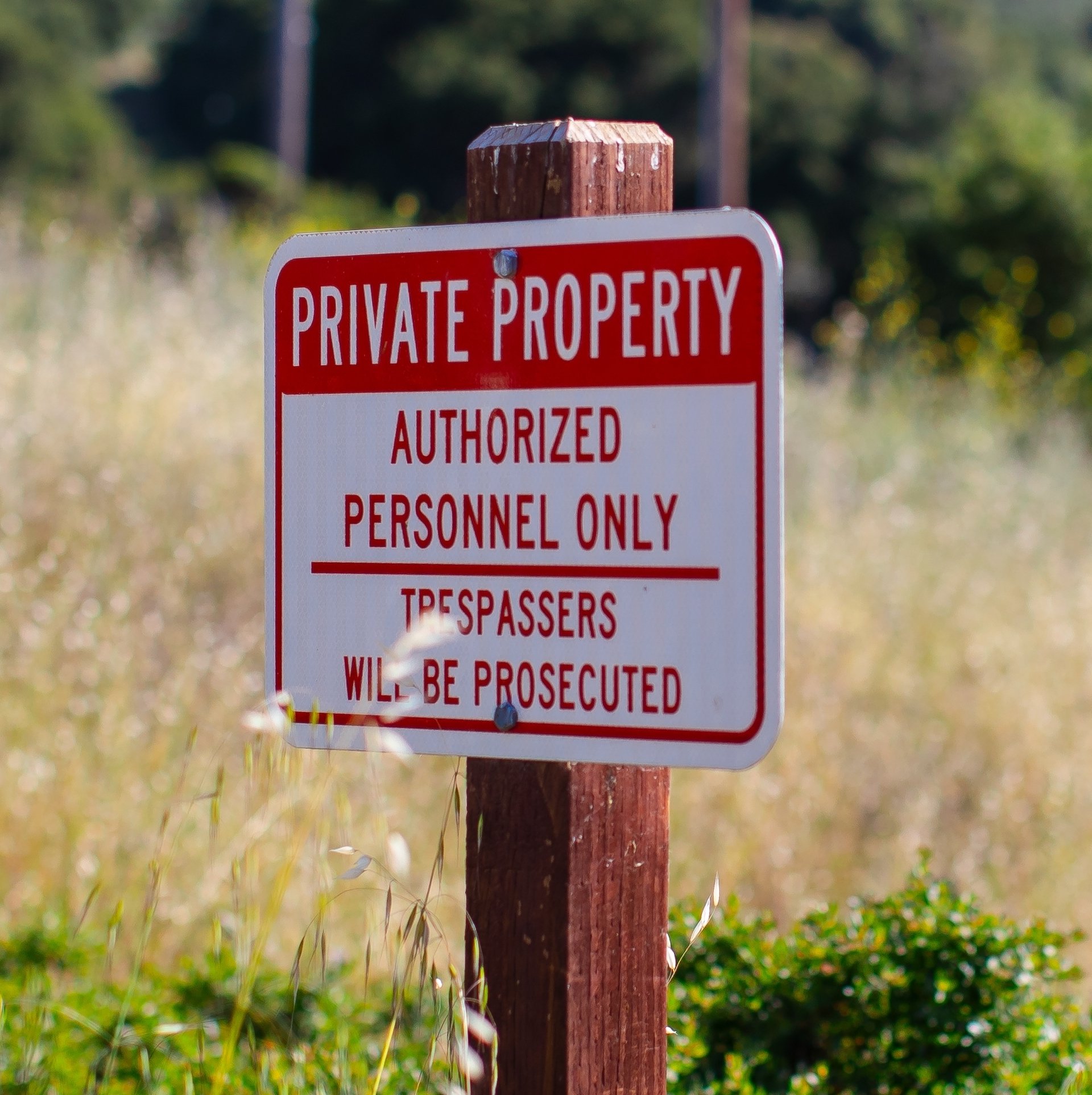 Private property no trespassing sign posted on an empty field