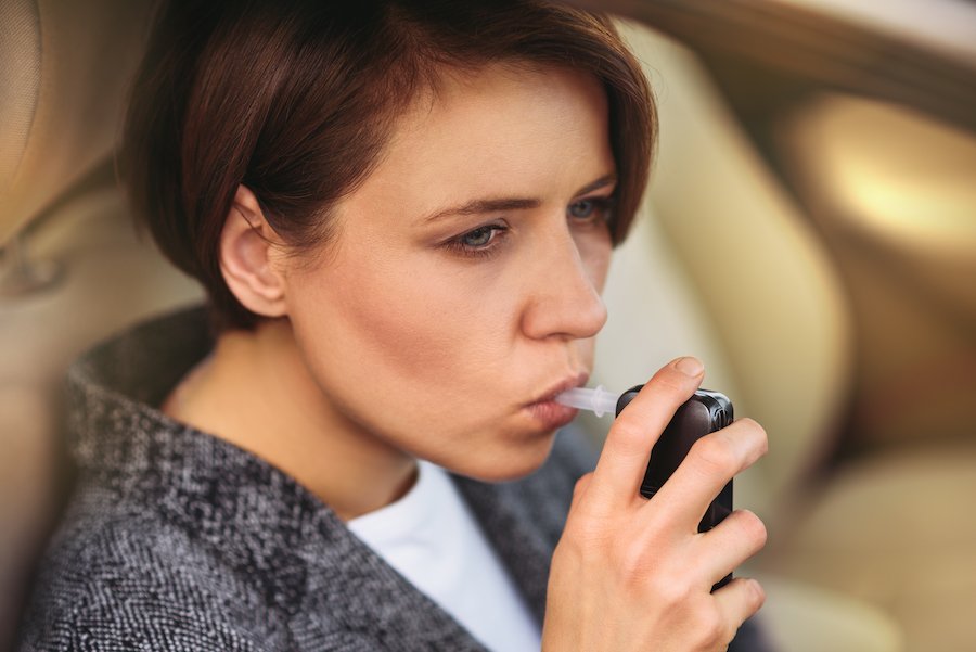 Young woman blowing into IID in order to start her car