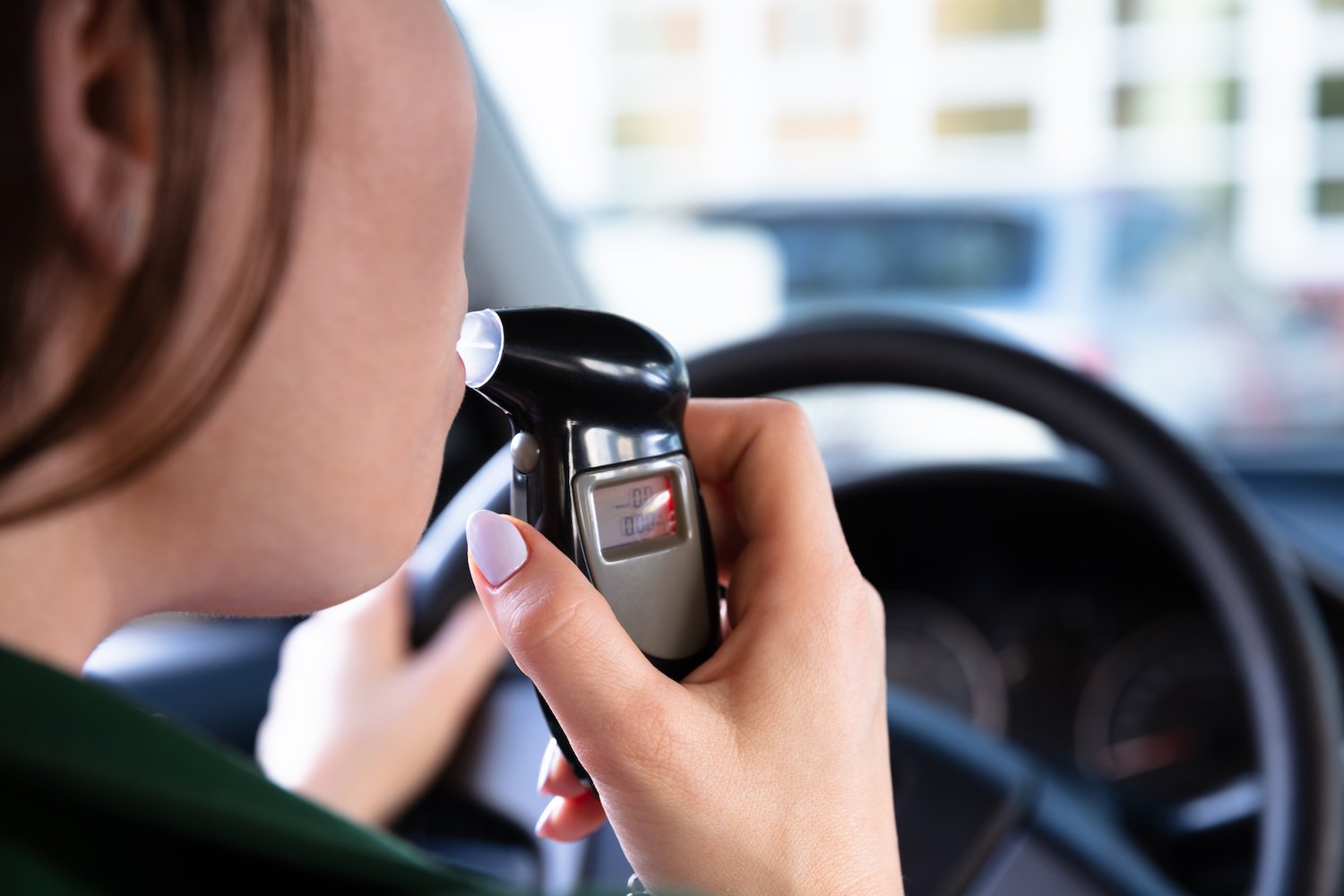 Close-up of female driver's mouth as she takes a breathalyzer test in a car