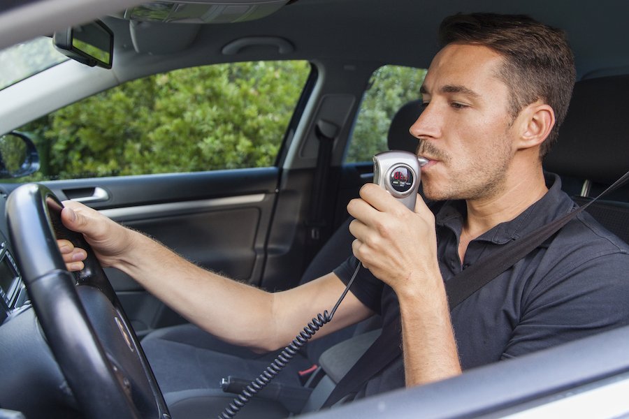 Man driving car while blowing into his ignition interlock device