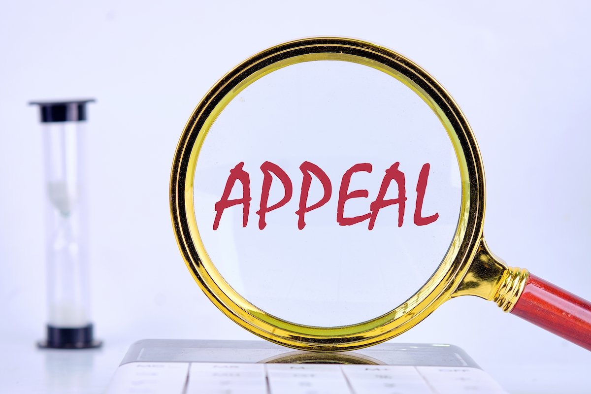 Magnifying glass over a sign that says "appeal" next to an hour glass against a white background