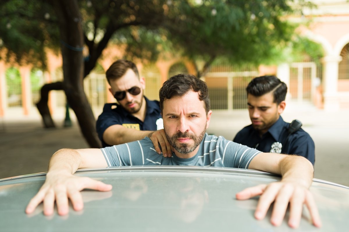 Man being thrown against the car during an arrest