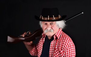 Menacing-looking bounty hunger slinging a rifle over his shoulder against a black background