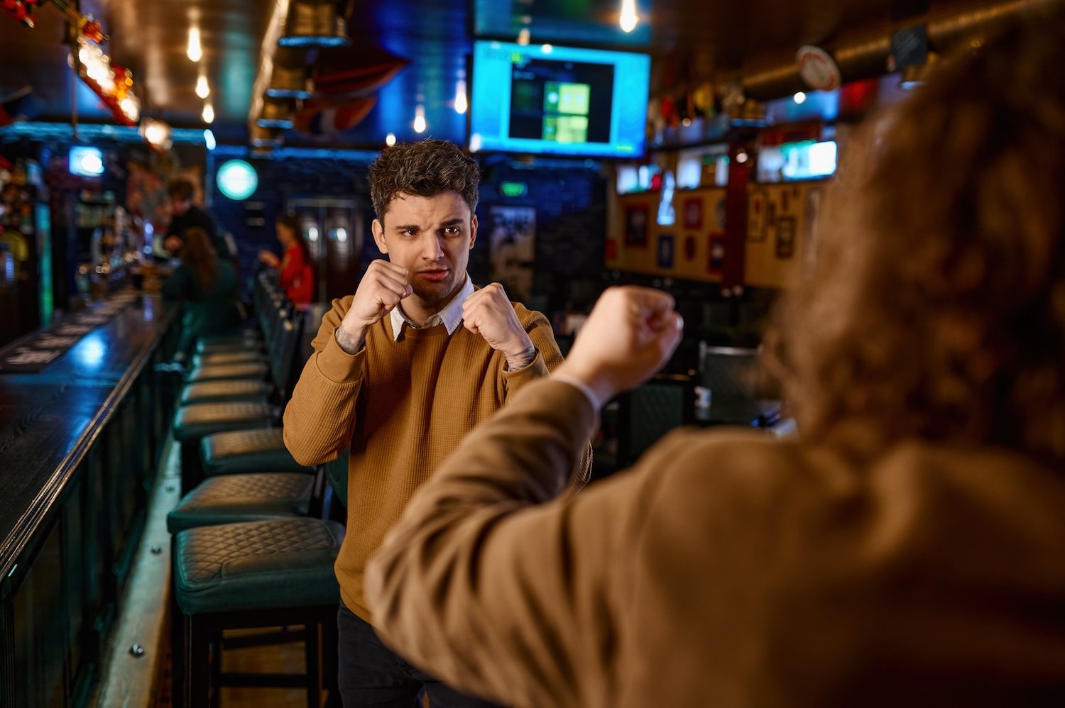 Two men fist-fighting in a bar about to commit disorderly conduct