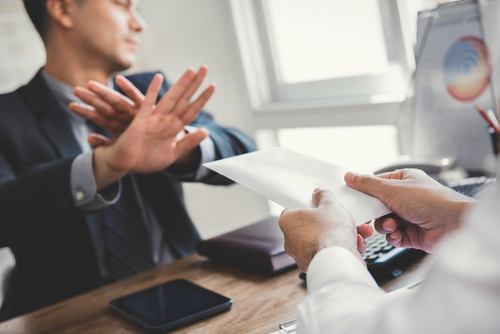 Man trying to pass an envelope to another man to illustrate bribery of a witness per Colorado CRS 18-8-703