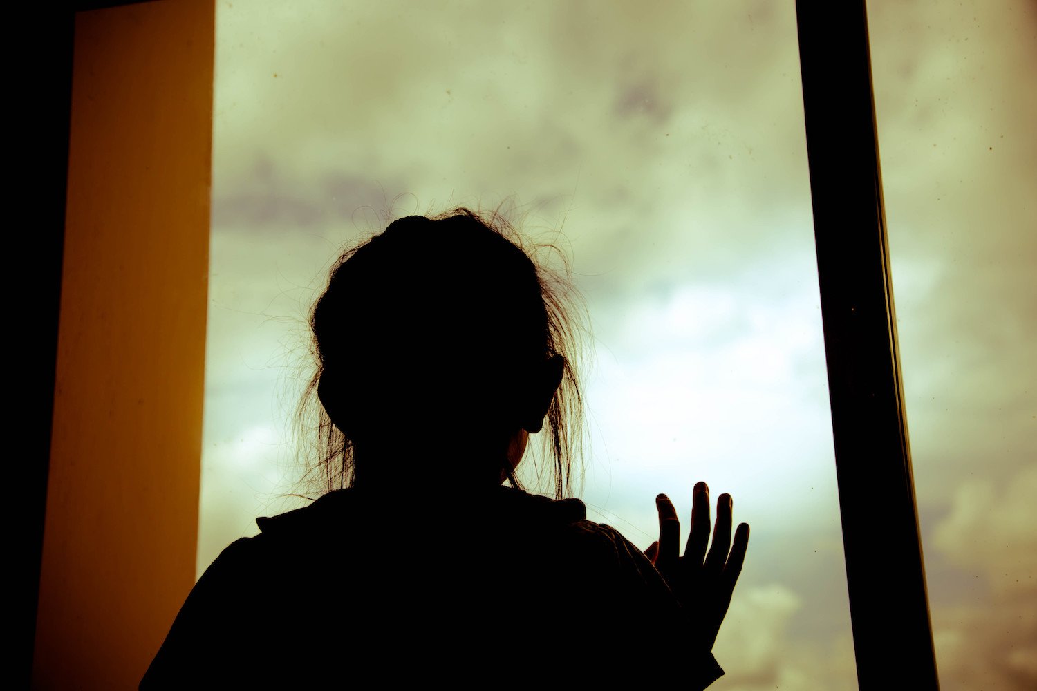 Silhouette of child against a window while being harbored
