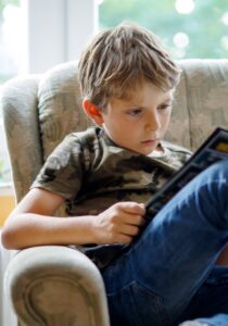 Child reading magazine on armchair