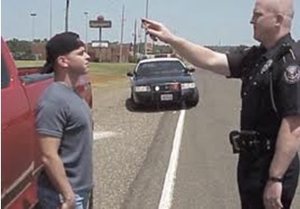 police administering horizontal gaze nystagmus test to a DUI suspect on the side of a road during the day