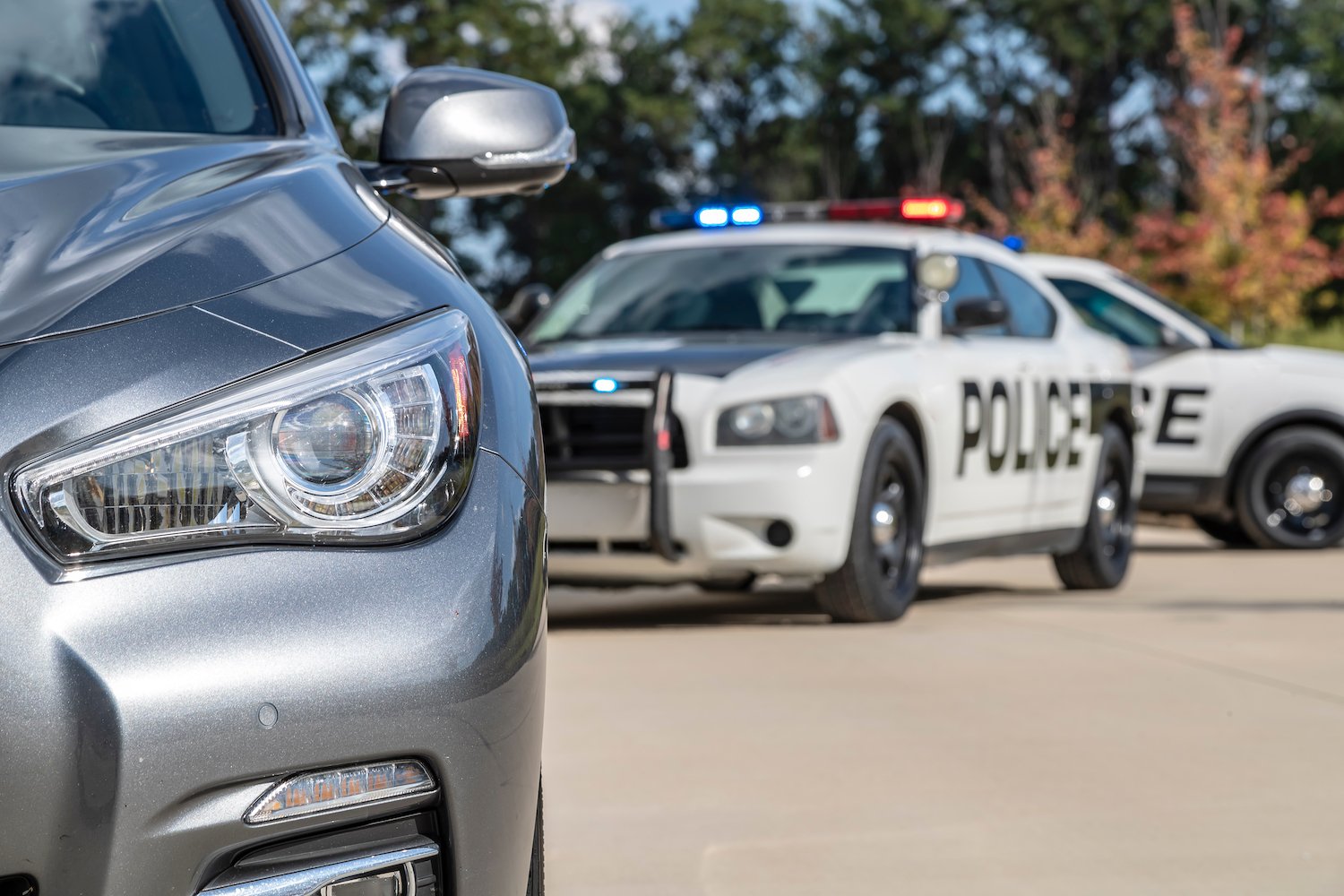 Two police vehicles stop a sedan on for a DUI traffic stop during the day