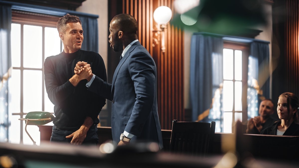Attorney and client shaking hands after a legal victory in the courtroom where his rape charge is dropped due to a lapsed statute of limitations