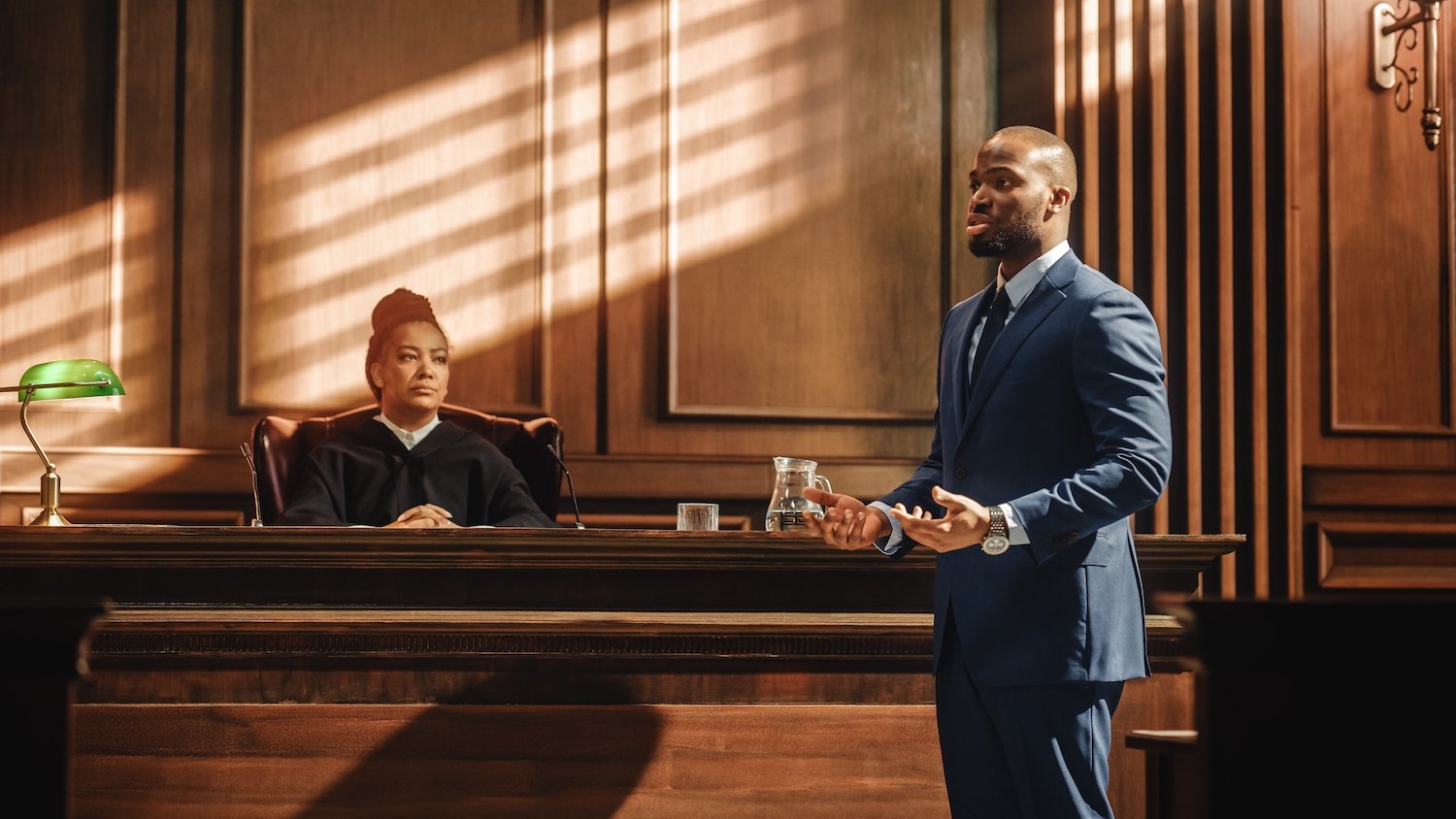 Attorney giving opening arguments in front of a judge in a wooden courtroom