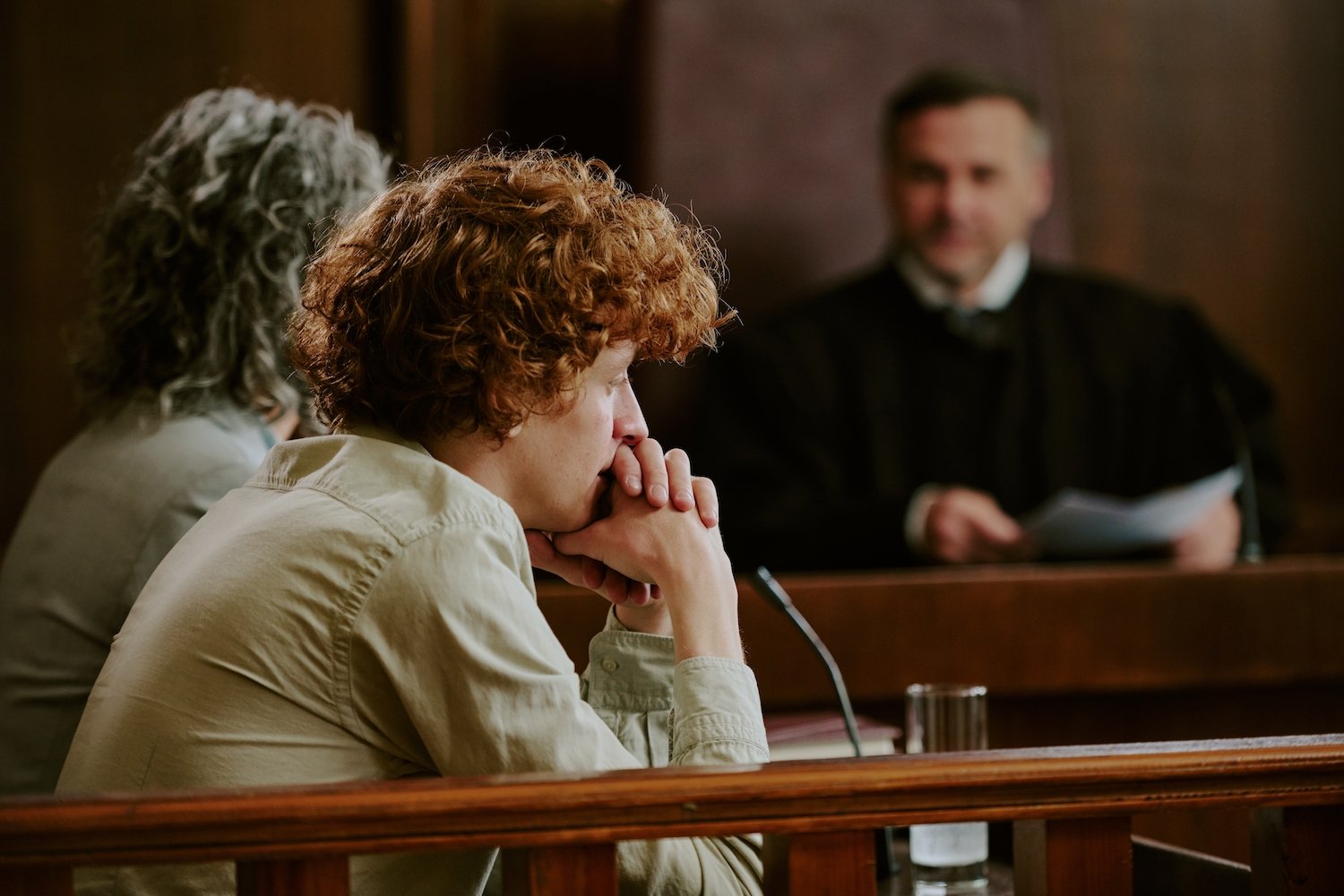 Defendant looking distressed during his courtroom trial with the judge in the background
