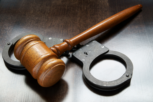 handcuffs and gavel on a wooden table