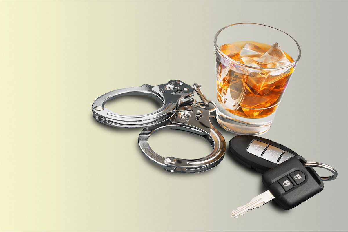 Tumbler with alcohol, handcuffs, and car keys to signify a DUI