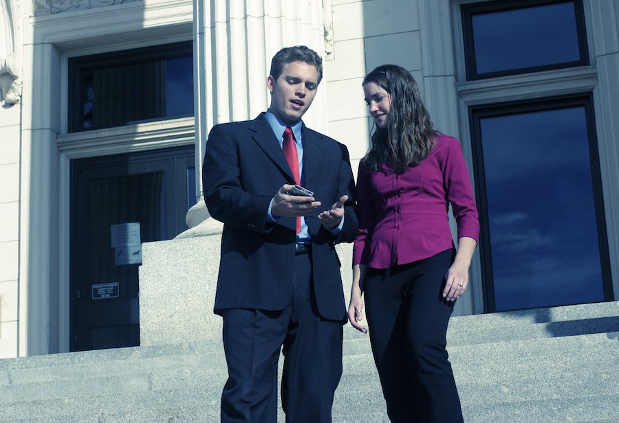 Happy diversion defendant with her attorney standing on the courthouse steps, and they are looking at his phone