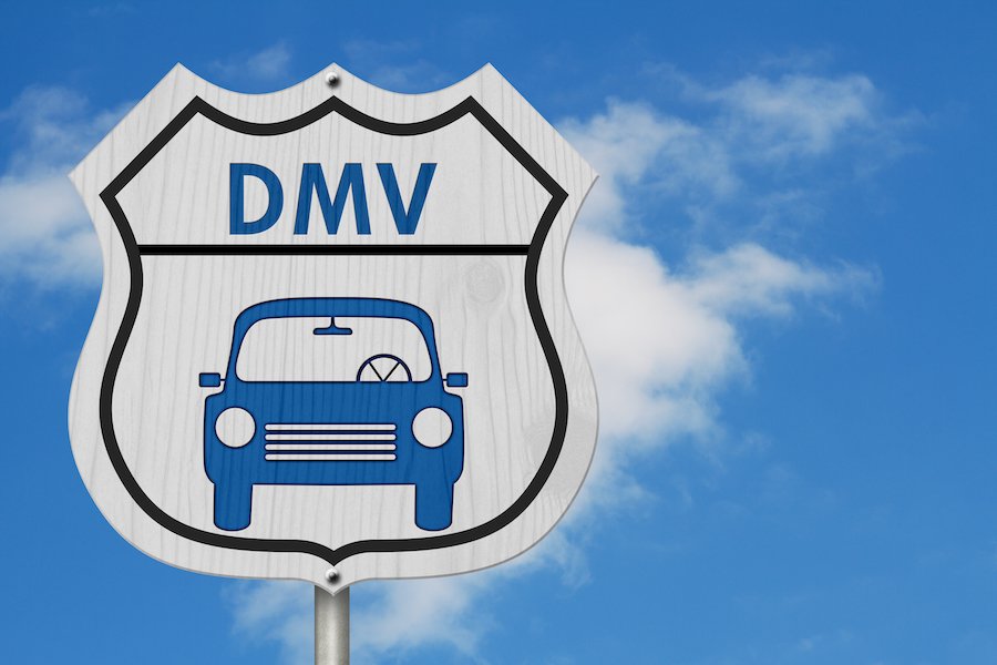 Sign that says "DMV" with a car graphic against a blue cloudy sky