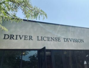 Exterior photograph of a DMV office with signage saying in allcaps, "Driver License Division."