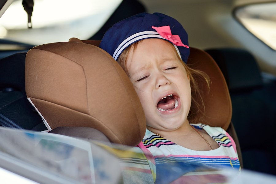 Crying child in car seat because her parent is driving while under the influence