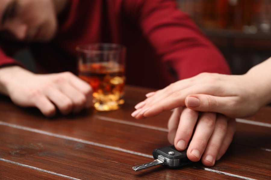 Man at bar with a drink, and his friend his preventing him from taking his car keys