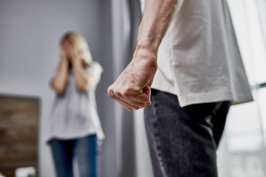 Man holding his hand in a first in front of his scared wife in their living room