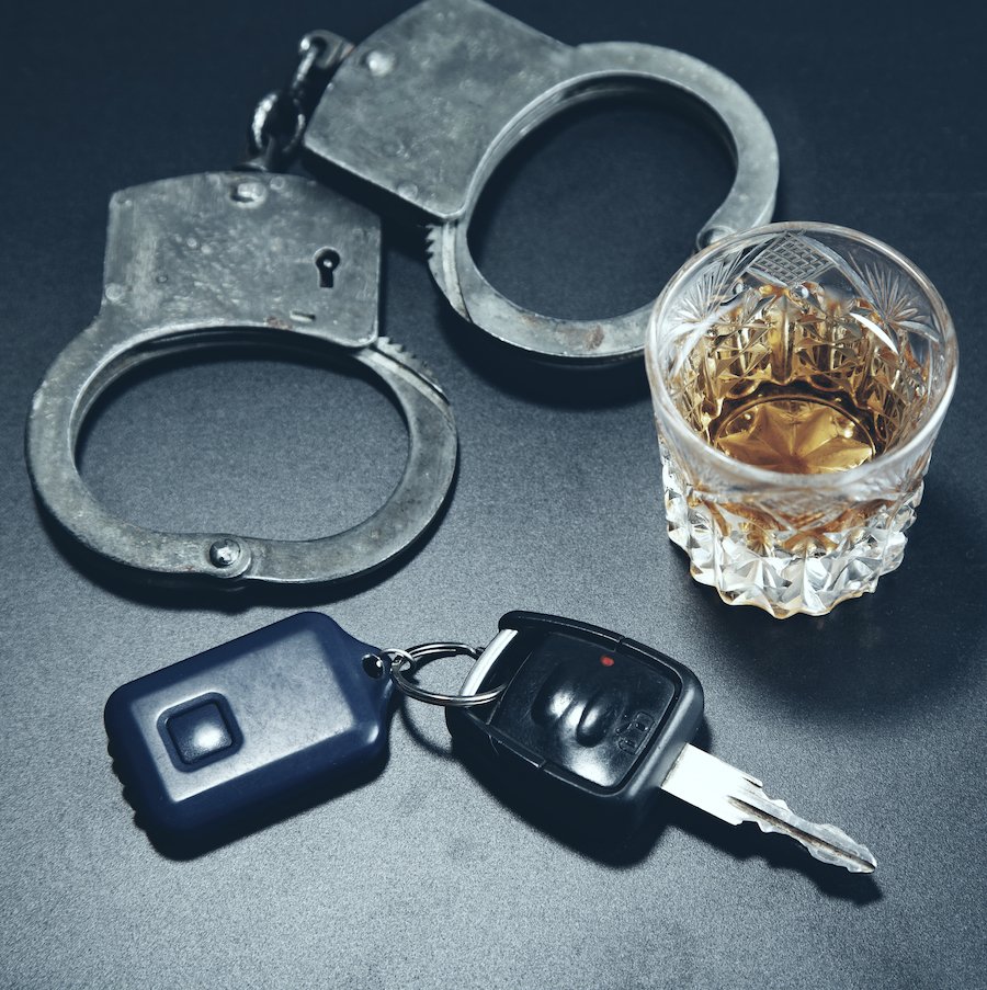 handcuffs, a tumbler with alcohol, and car keys resting on a table, signifying DWAI
