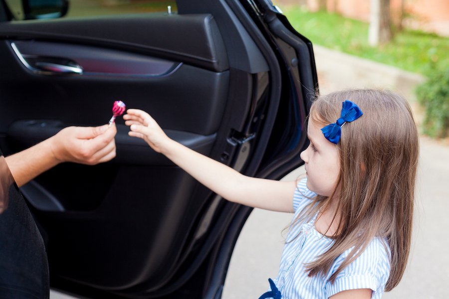 Stranger in a car luring a child with a lollipop