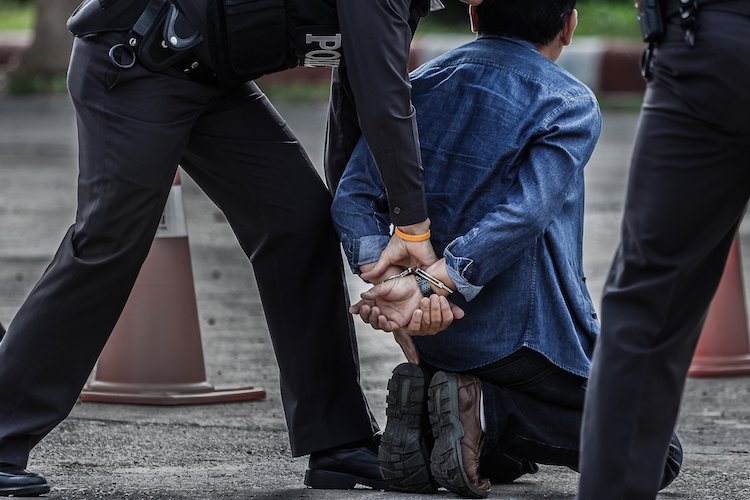 Man being handcuffed by a police officer - Colorado extradition law can compel other states to return fugitives 