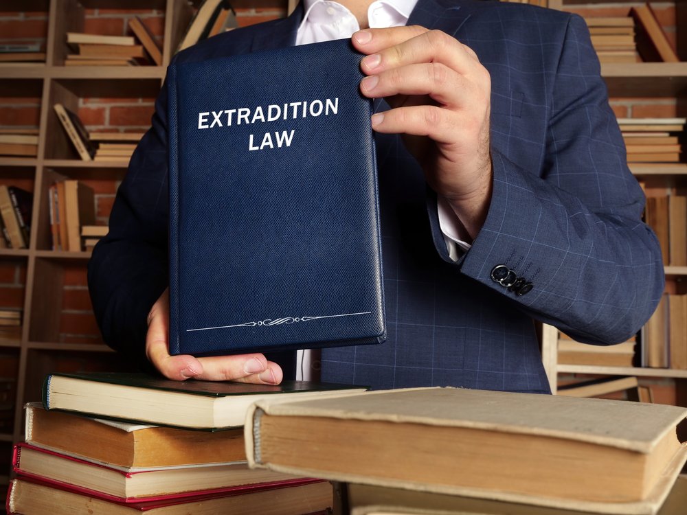 Person holding up an Extradition Law book.