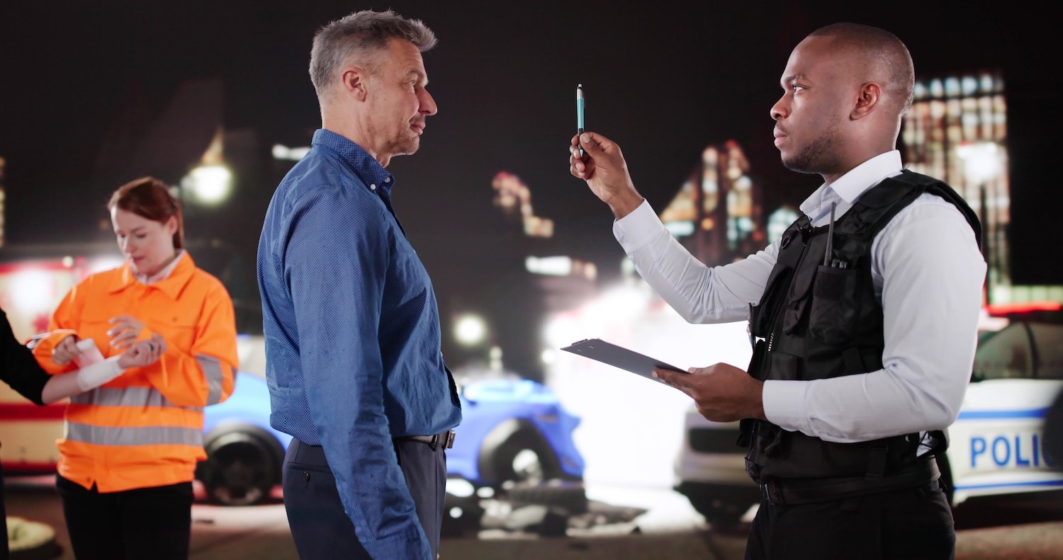 Man undergoing horizontal gaze nystagmus test at a DUI traffic stop at night