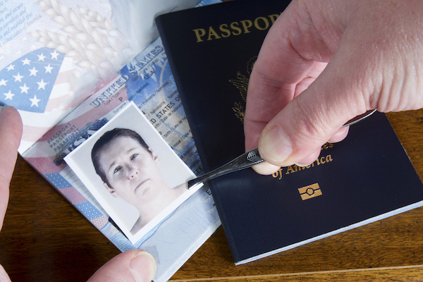 Close-up of hands forging a passport by pasting on the wrong photo. 