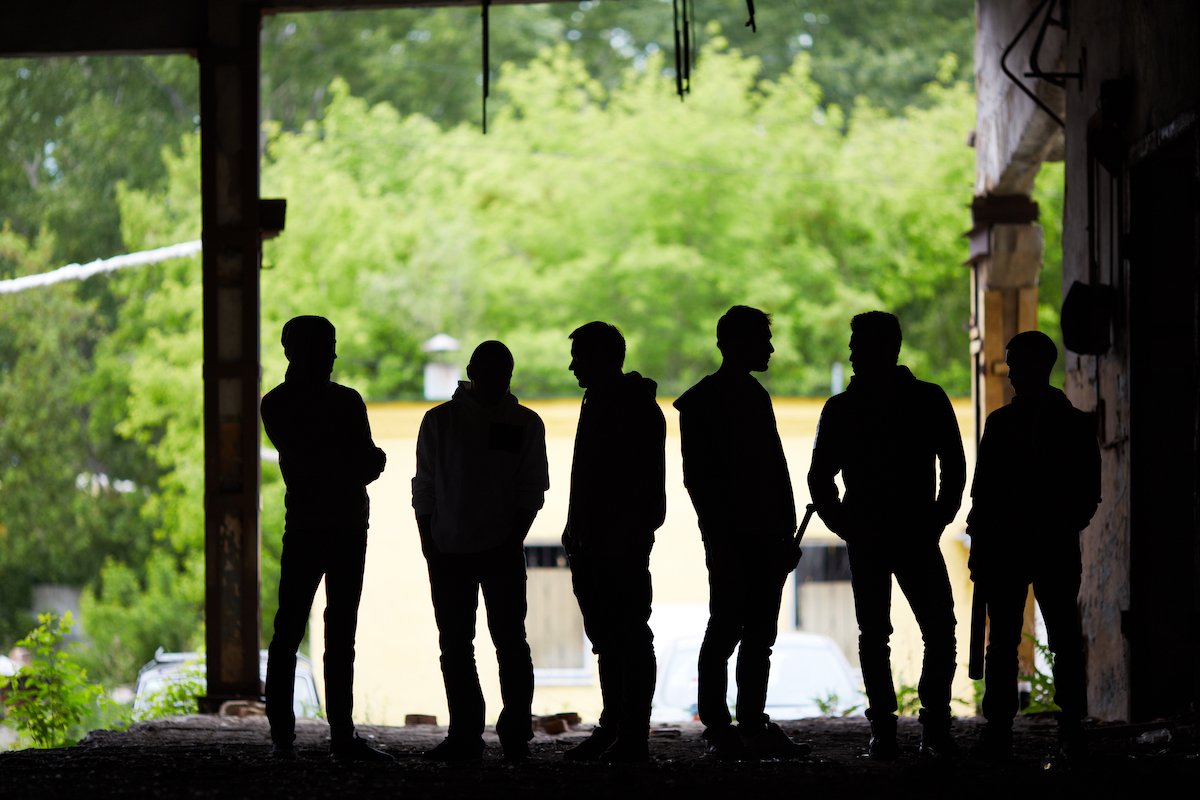 Silhouettes of gang members under an overpass
