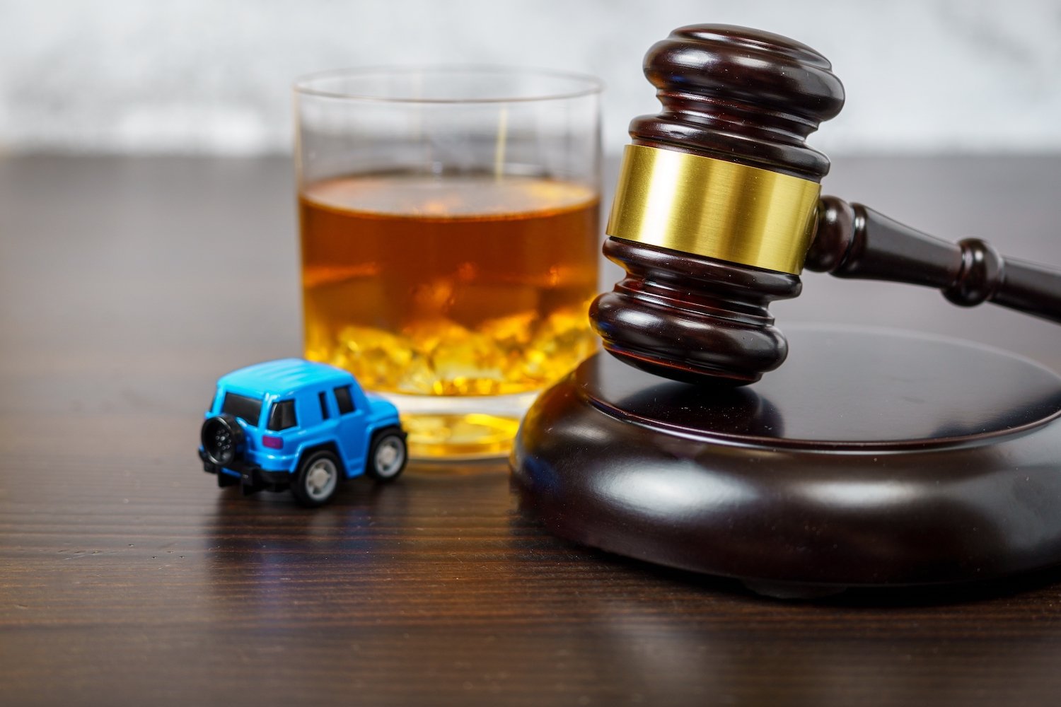 Gavel, tumbler of alcohol, and a toy car signifying a DUI