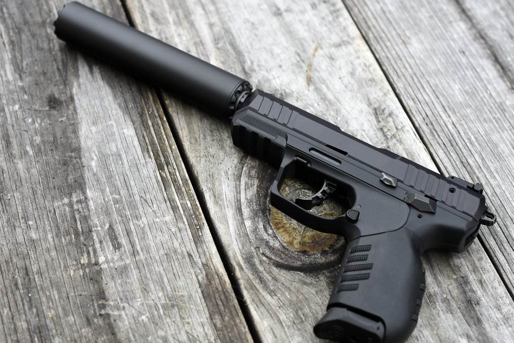 Una pistola con un silenciador adjunto sobre una mesa de madera