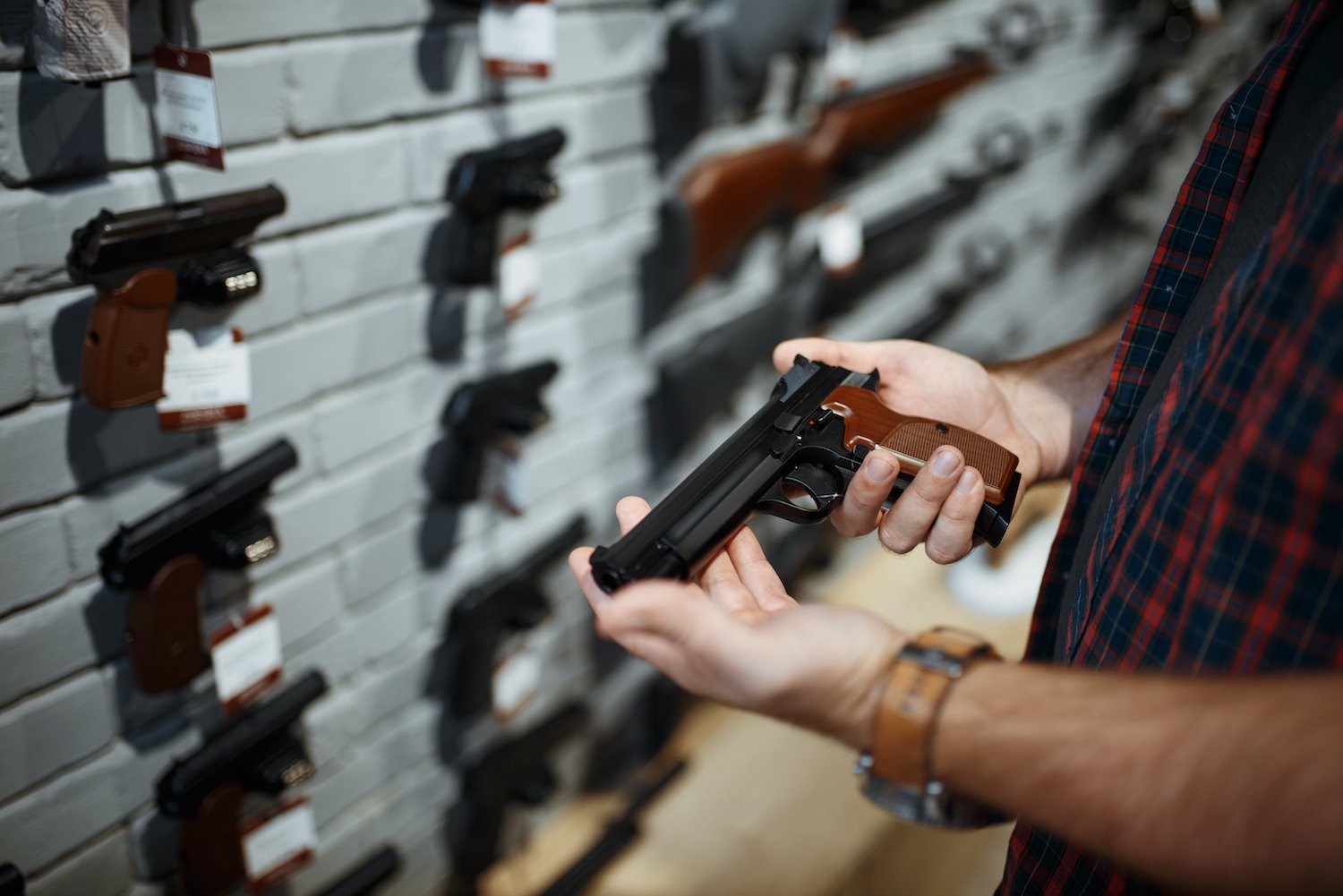 Man holding a revolver in a gun store contemplating buying it