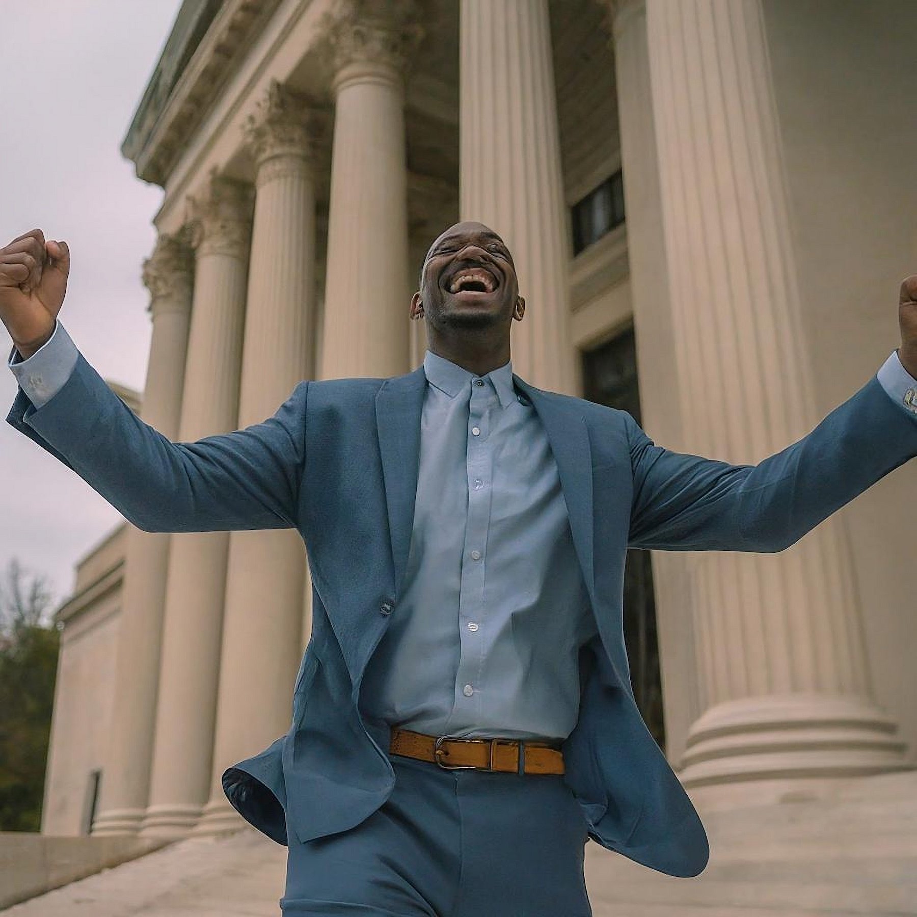 Man pumping his fists in victory outside of a courthouse following a legal win