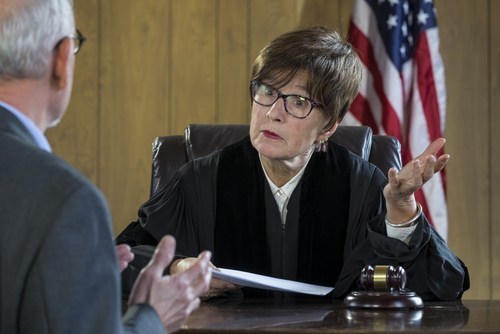 Judge talking to attorney during a sentencing hearing with an American flag behind her and a gavel underneath her hand