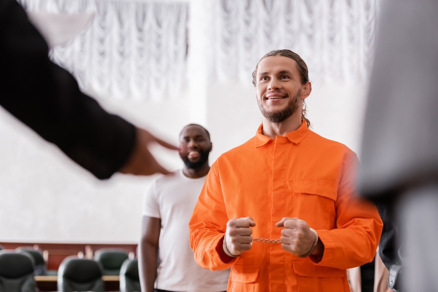 Inmate in orange jumpsuit in a courtroom during a proceeding