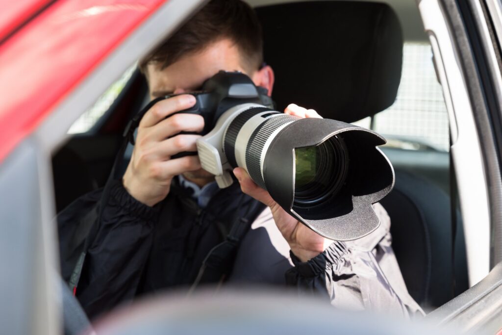 Private eye in car holding a telephoto lens