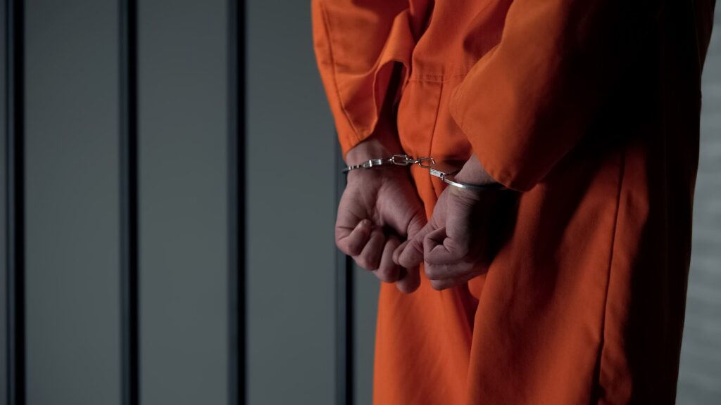 Man in handcuffs while serving a class 1 felony life sentence. 